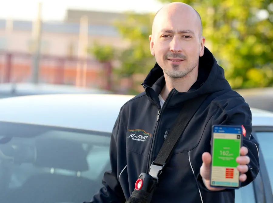 Sachverständiger von KS-XPERT zeigt das Ergebnis einer Lackschichtmessung auf dem Handy